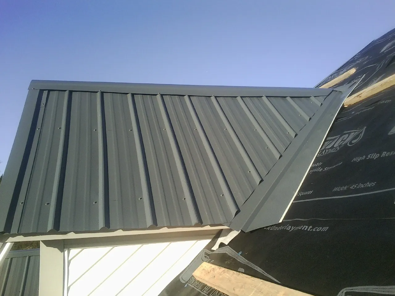 Gray metal roof panels going on over a garage gable in Paupack