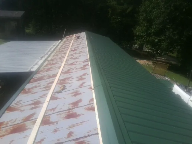 Old rusted panels beside newly installed green metal roofing — Wind Damage Roof Repair by Roofing Brothers in Paupack