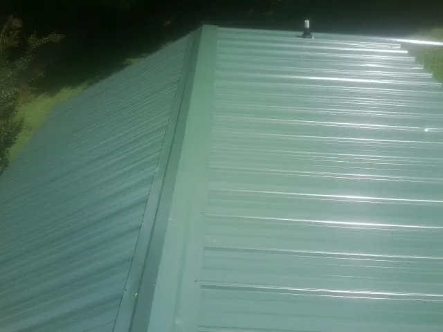 New green metal panels meeting at the ridge of a roof — Flat Roof Repair work by our crew in Paupack