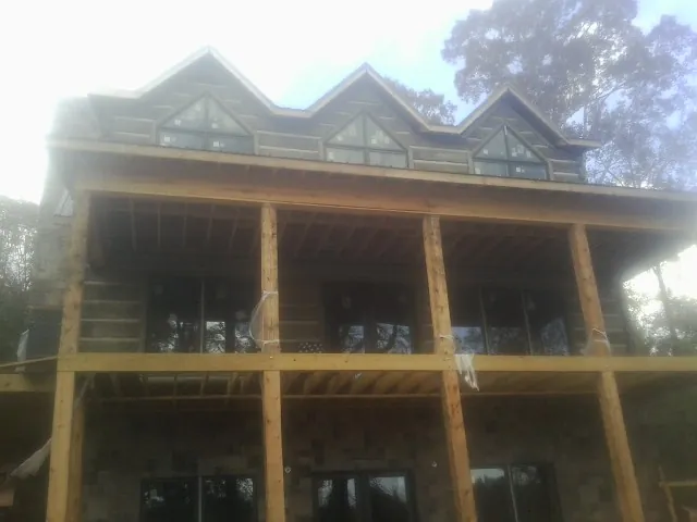 Dormers and porch framing on a large log home under construction — Roof Coating work by our crew in Paupack