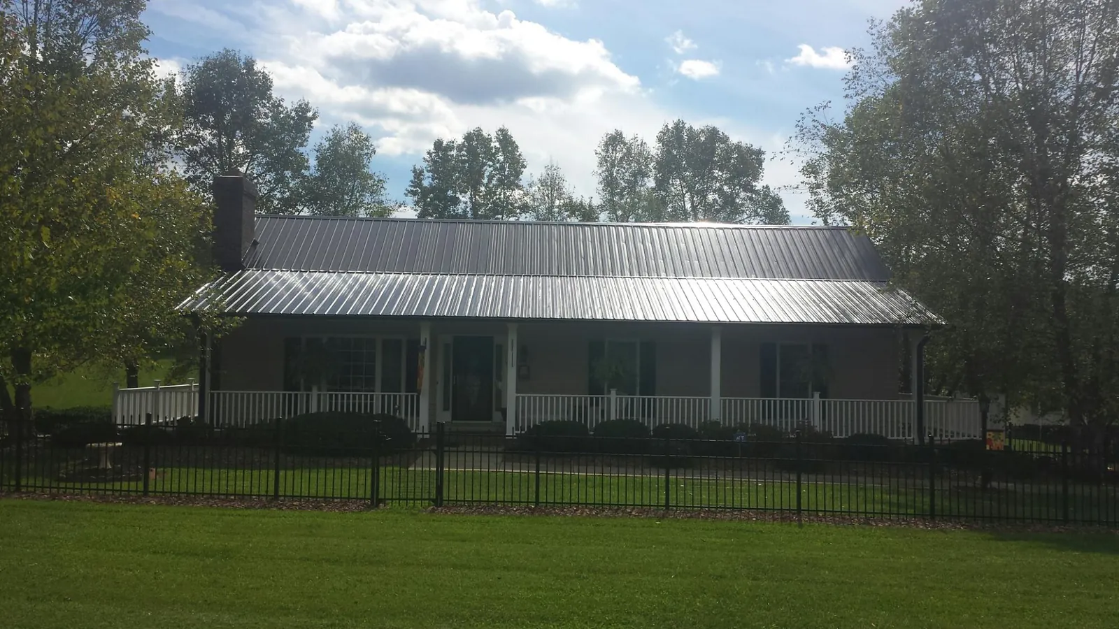 Gray metal roof on a brick ranch with a full width front porch — Gutter Guard Installation work by our crew in Paupack