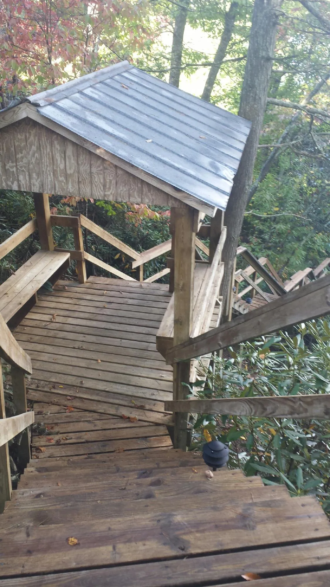 Metal roofed shelter over wooden steps on a wooded walkway — Skylight Repair & Installation work by our crew in Paupack