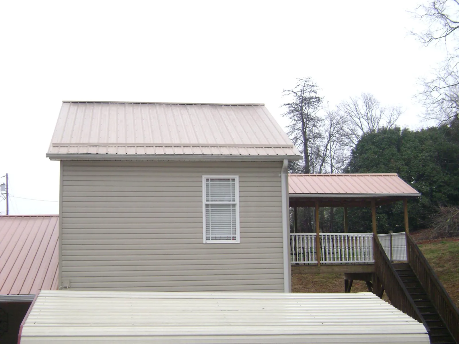 Tan metal roofs on a two story addition and attached porch, from a Roof Replacement job in Paupack