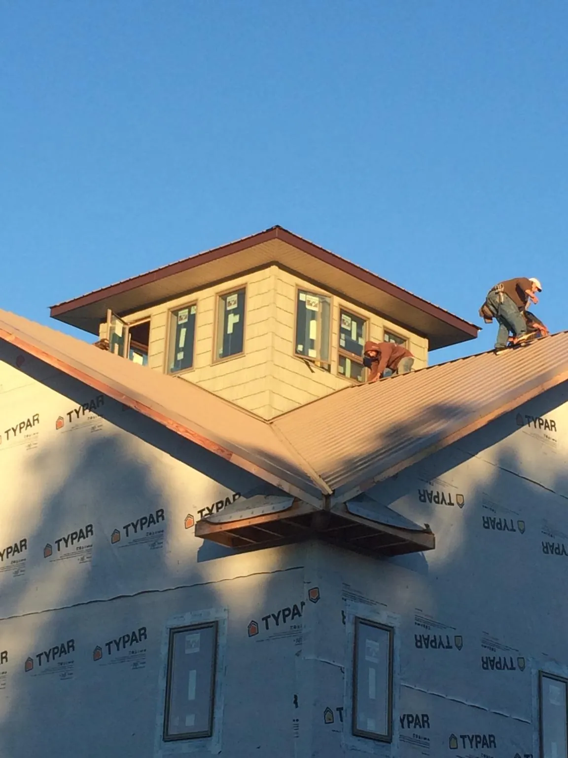 Roofers working around a rooftop cupola on a new metal roof at sunset — Roof Waterproofing in Paupack by Roofing Brothers